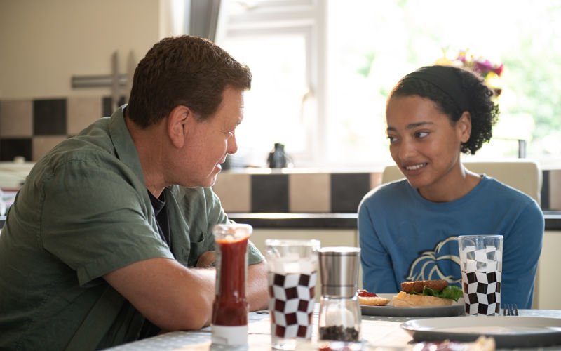 Young girl sat at the kitchen table with foster dad